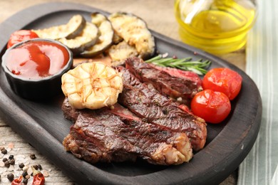 Photo of Delicious grilled beef with vegetables, tomato sauce and spices on table, closeup