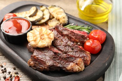 Delicious grilled beef with vegetables, tomato sauce and spices on table, closeup