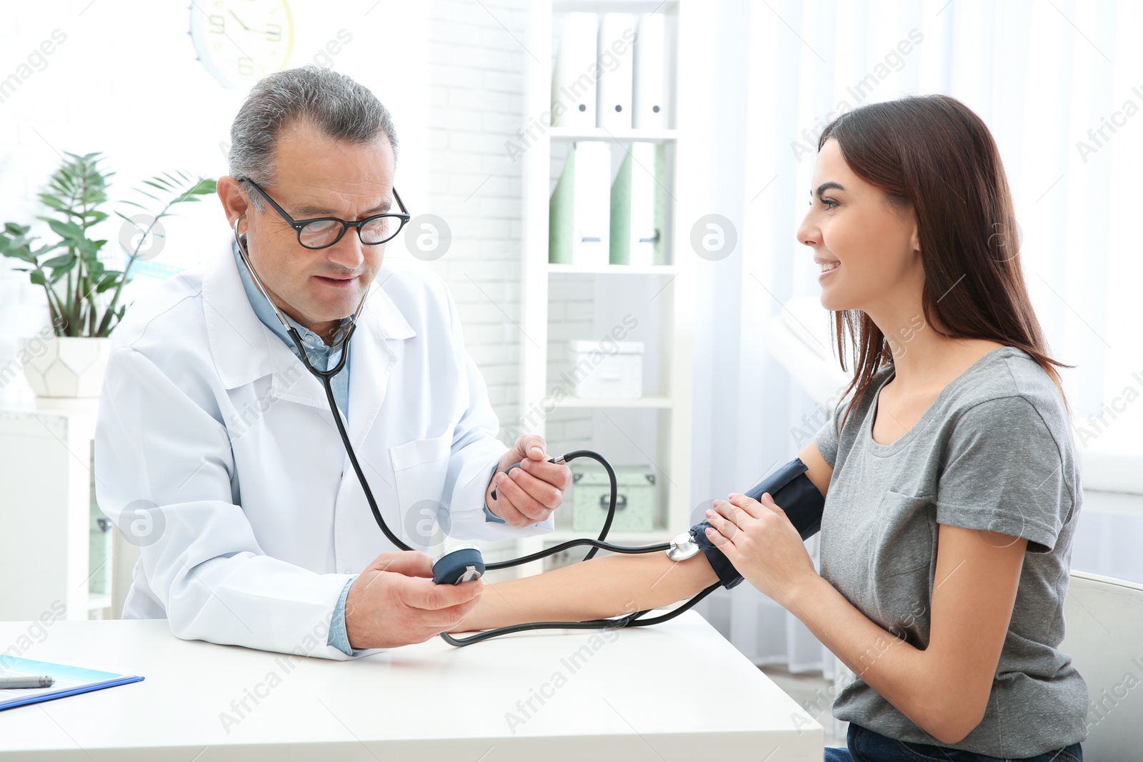 Photo of Young woman visiting doctor in hospital. Measuring blood pressure and checking pulse