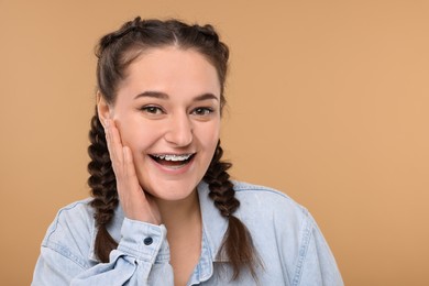 Photo of Smiling woman with braces on beige background. Space for text