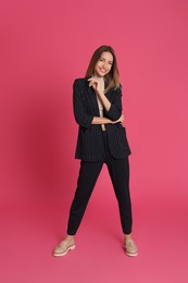 Full length portrait of beautiful young woman in fashionable suit on pink background. Business attire