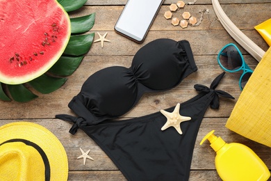 Composition with beach accessories and bikini on wooden background, flat lay