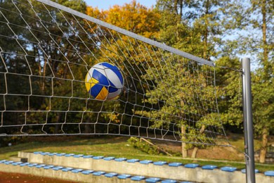 Photo of Ball hitting into volleyball net on court outdoors