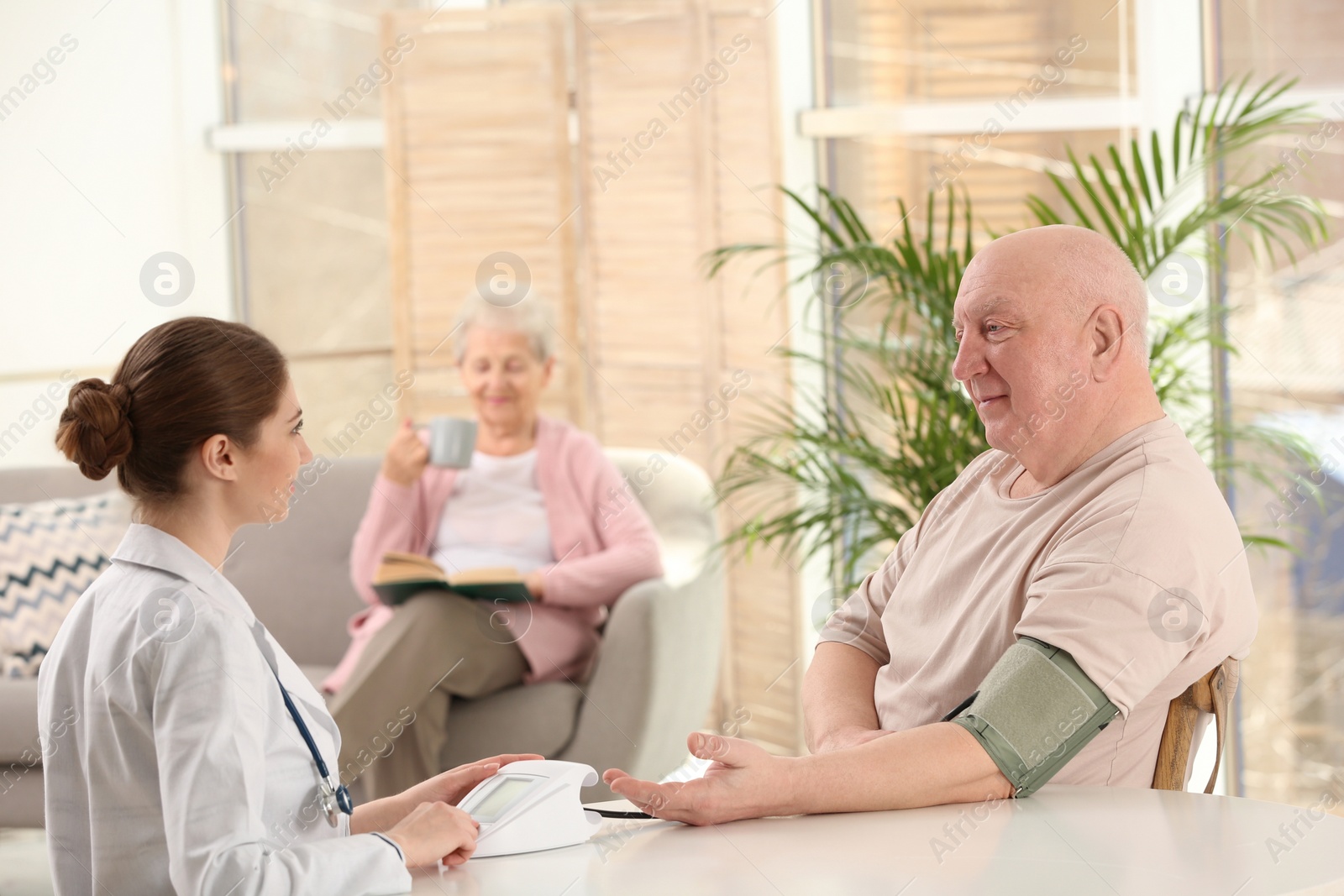 Photo of Nurse measuring blood pressure of elderly man indoors. Assisting senior generation