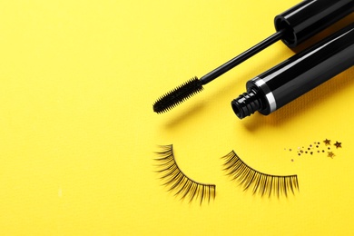 Photo of False eyelashes and mascara on yellow background, space for text