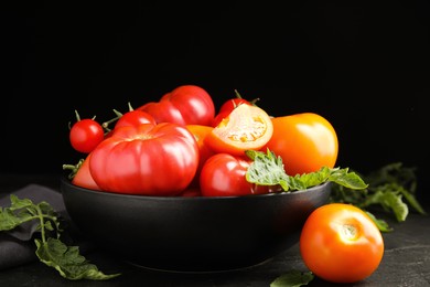 Photo of Many different ripe tomatoes with leaves on black table
