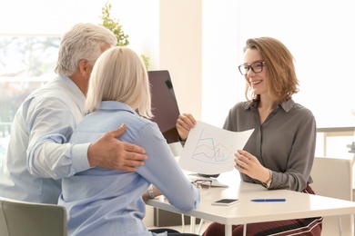 Photo of Female manager consulting mature couple in office
