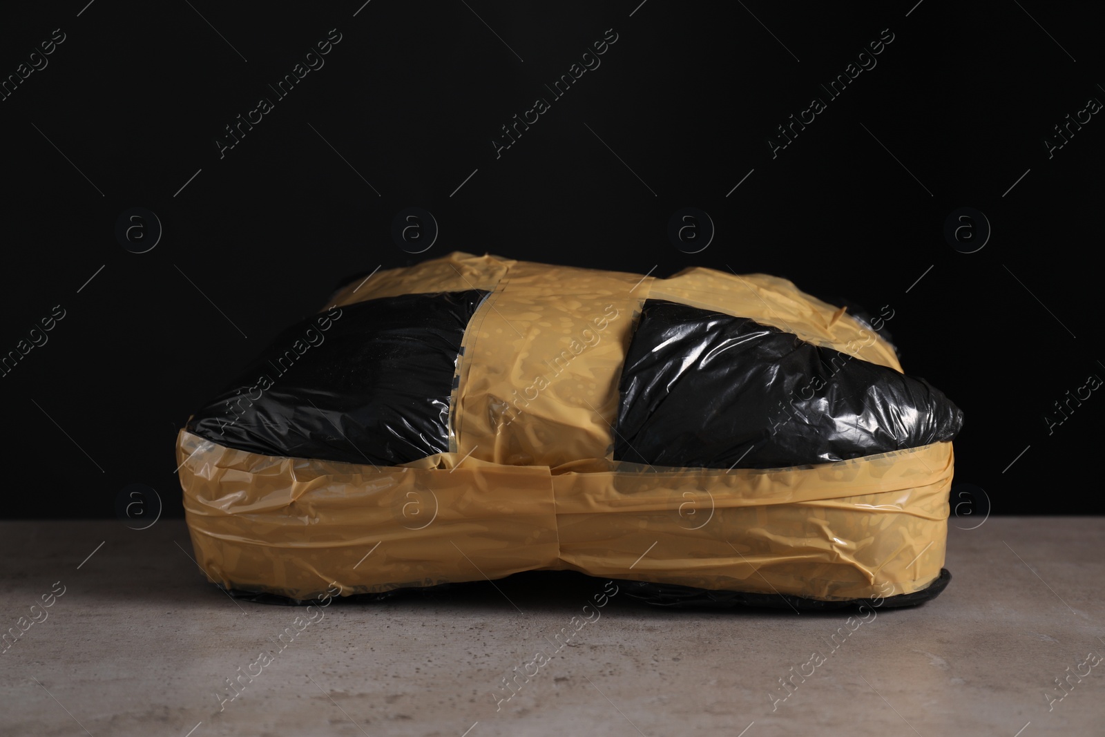 Photo of Smuggling and drug trafficking. Package with narcotics on grey table against black background