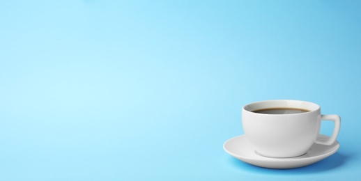 Photo of White ceramic cup with hot aromatic coffee on color background