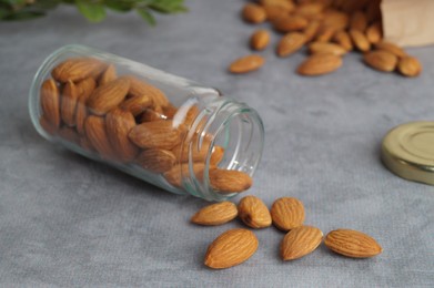 Jar with delicious almonds on grey table