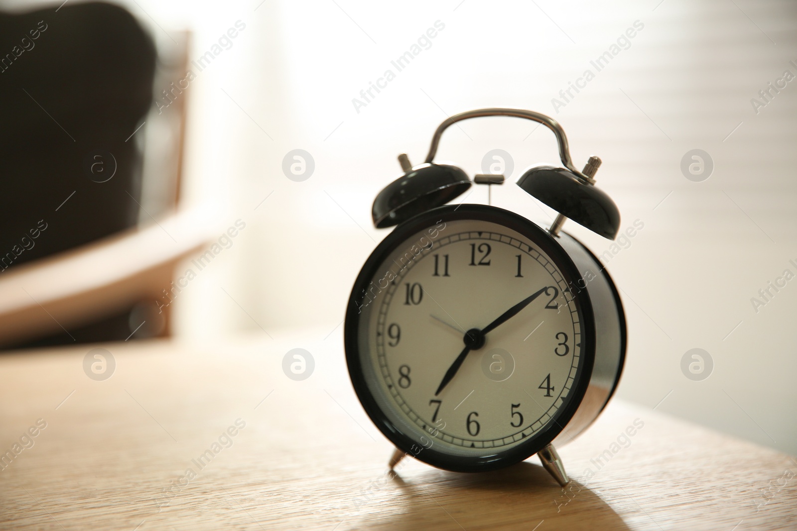 Photo of Alarm clock on wooden table at home. Morning time