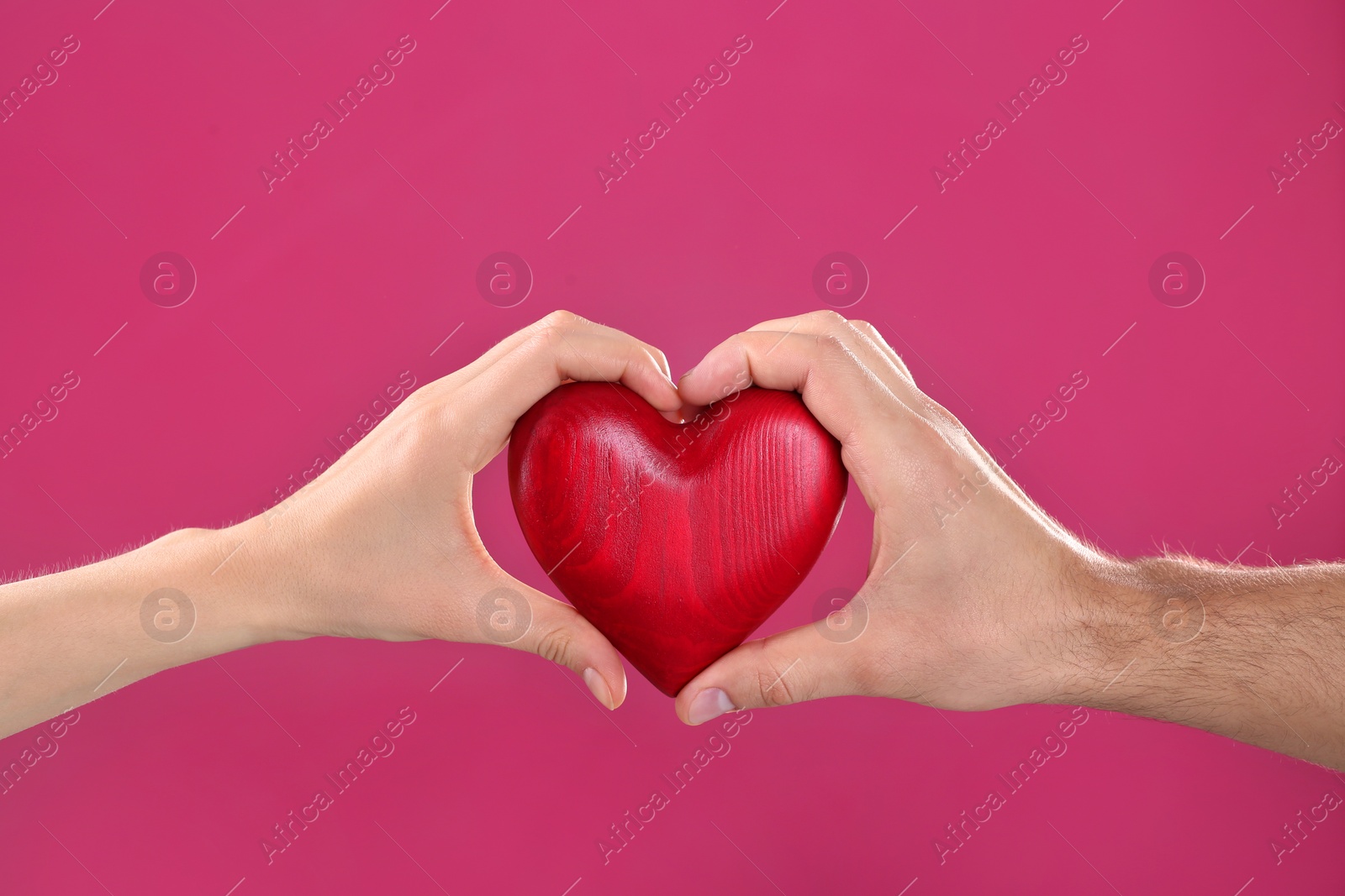 Photo of Man and woman holding decorative heart on color background, closeup