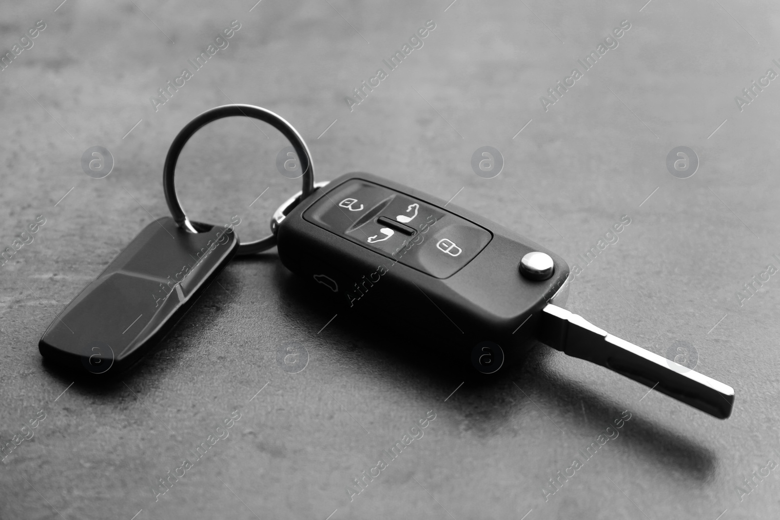 Modern car flip key with trinket on grey background, closeup Photo of Modern car flip key with trinket on grey background, closeup