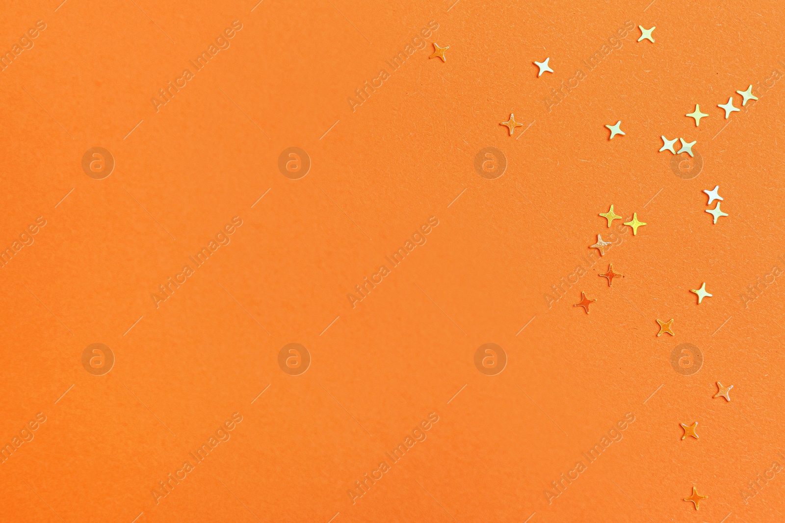 Photo of Shiny bright glitter on orange background, flat lay. Space for text