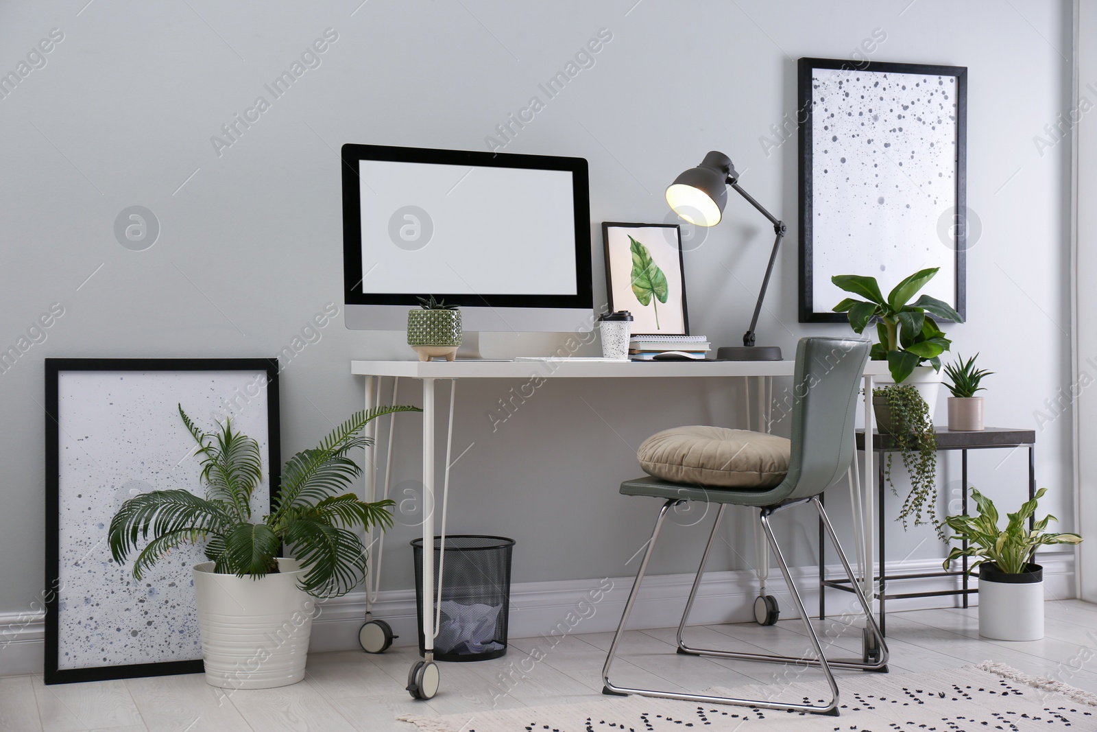 Photo of Comfortable workplace with modern computer and houseplants in room. Interior design