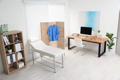 Modern medical office with doctor's workplace and examination table in clinic