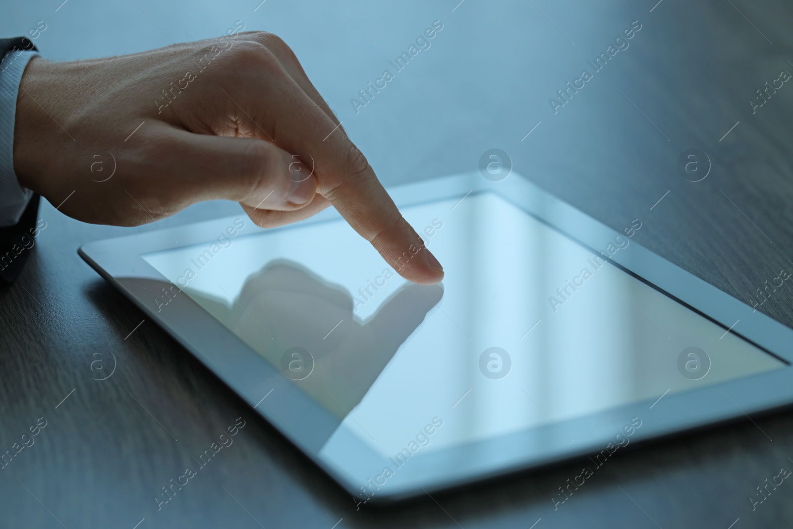 Photo of Man using tablet at wooden table, closeup