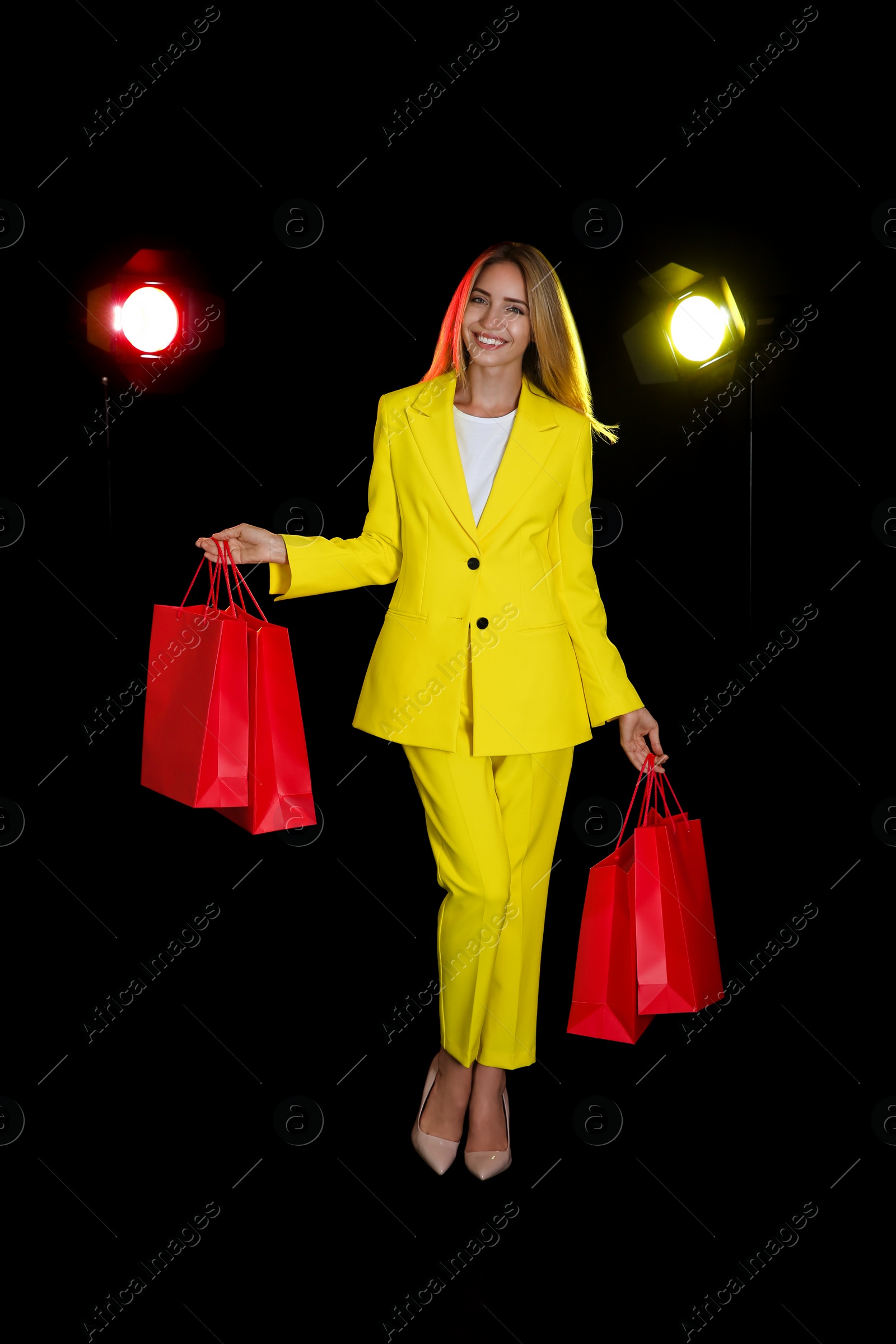 Photo of Happy young woman with shopping bags on dark background. Black Friday Sale