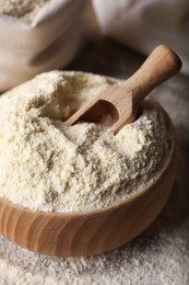 Wooden bowl with quinoa flour and scoop on table