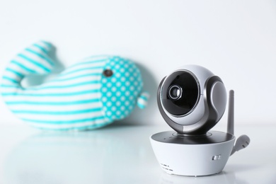 Modern CCTV security camera and toy whale on table against white background. Space for text