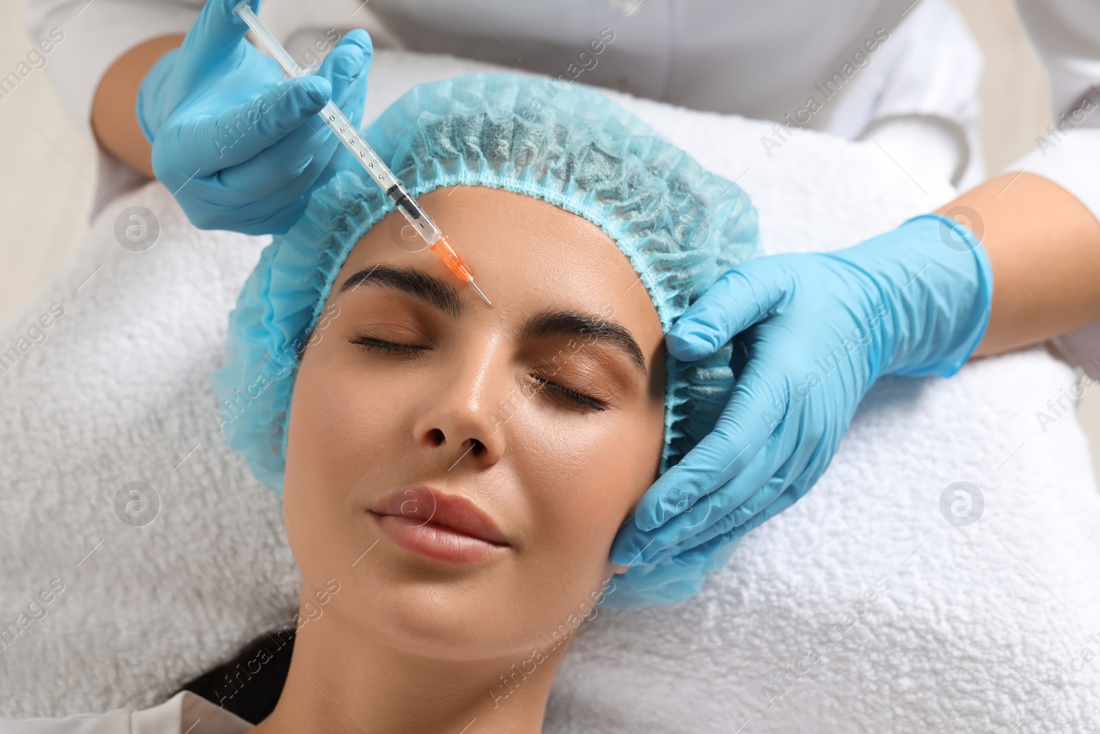 Photo of Doctor giving facial injection to young woman in clinic. Cosmetic surgery