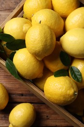 Photo of Fresh lemons in crate on wooden table, top view