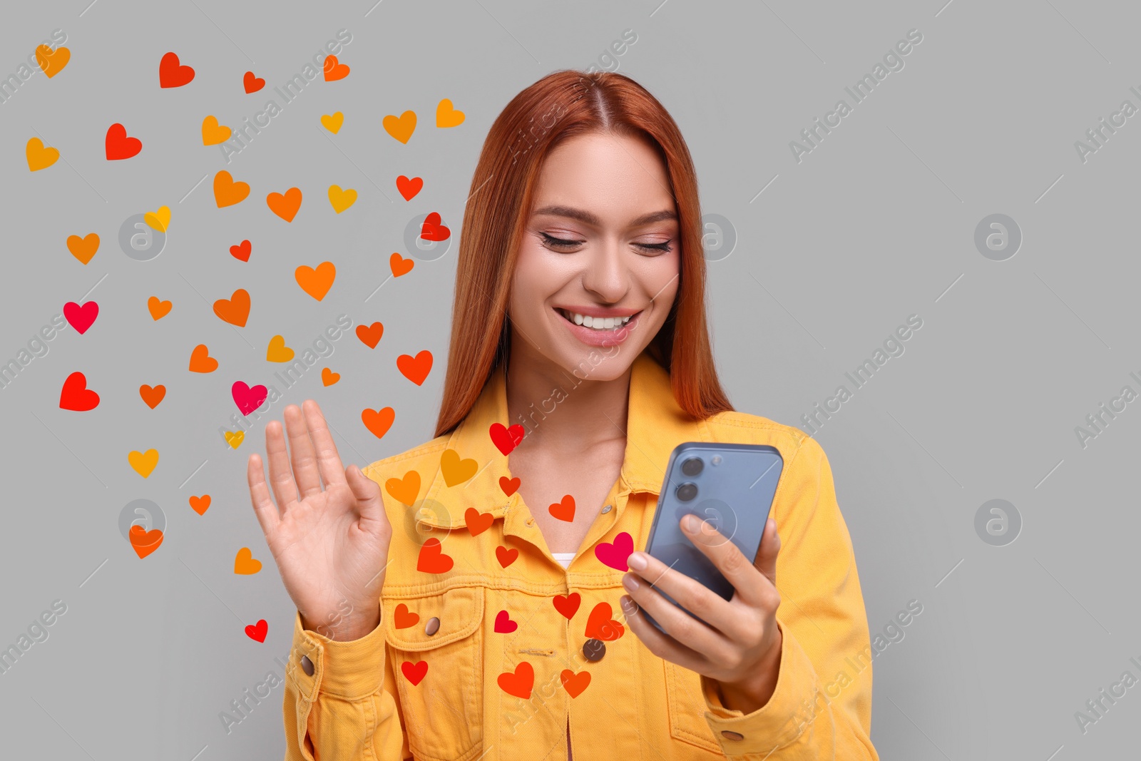 Image of Long distance love. Woman video chatting with sweetheart via smartphone on grey background. Hearts flying out of device