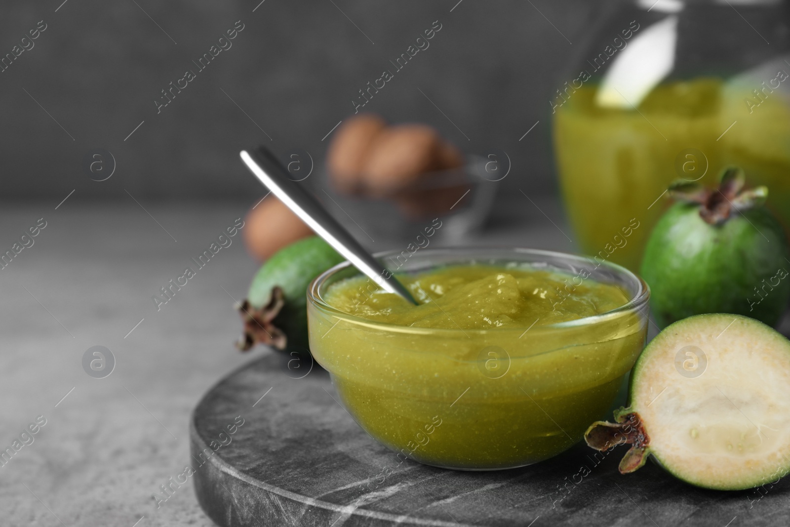 Photo of Feijoa jam on grey table, closeup. Space for text