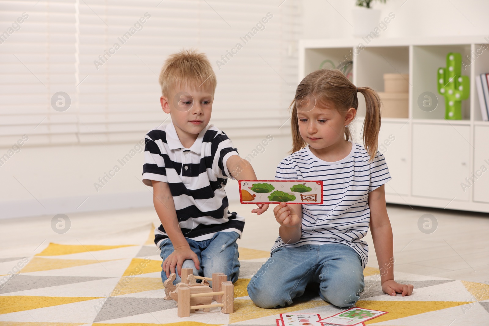 Photo of Little boy and girl playing with set of wooden animals indoors. Children's toys