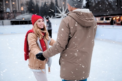 Image of Happy couple skating at outdoor ice rink
