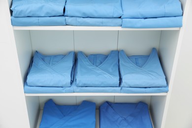 Photo of Light blue medical uniforms on white rack