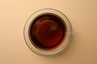 Photo of Cup of tea and anise star on beige background, top view