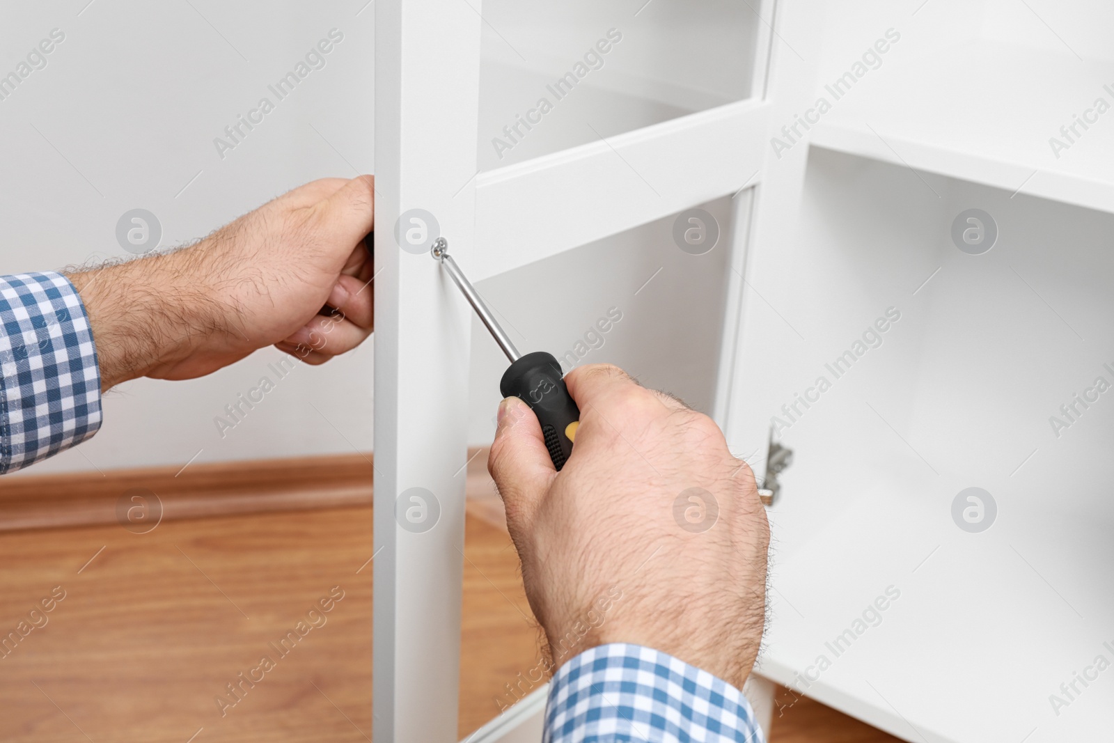 Photo of Man fixing handle of wooden cabinet, closeup view