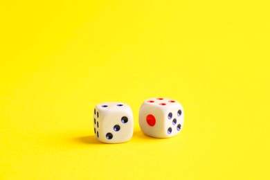 Photo of Two white game dices on yellow background