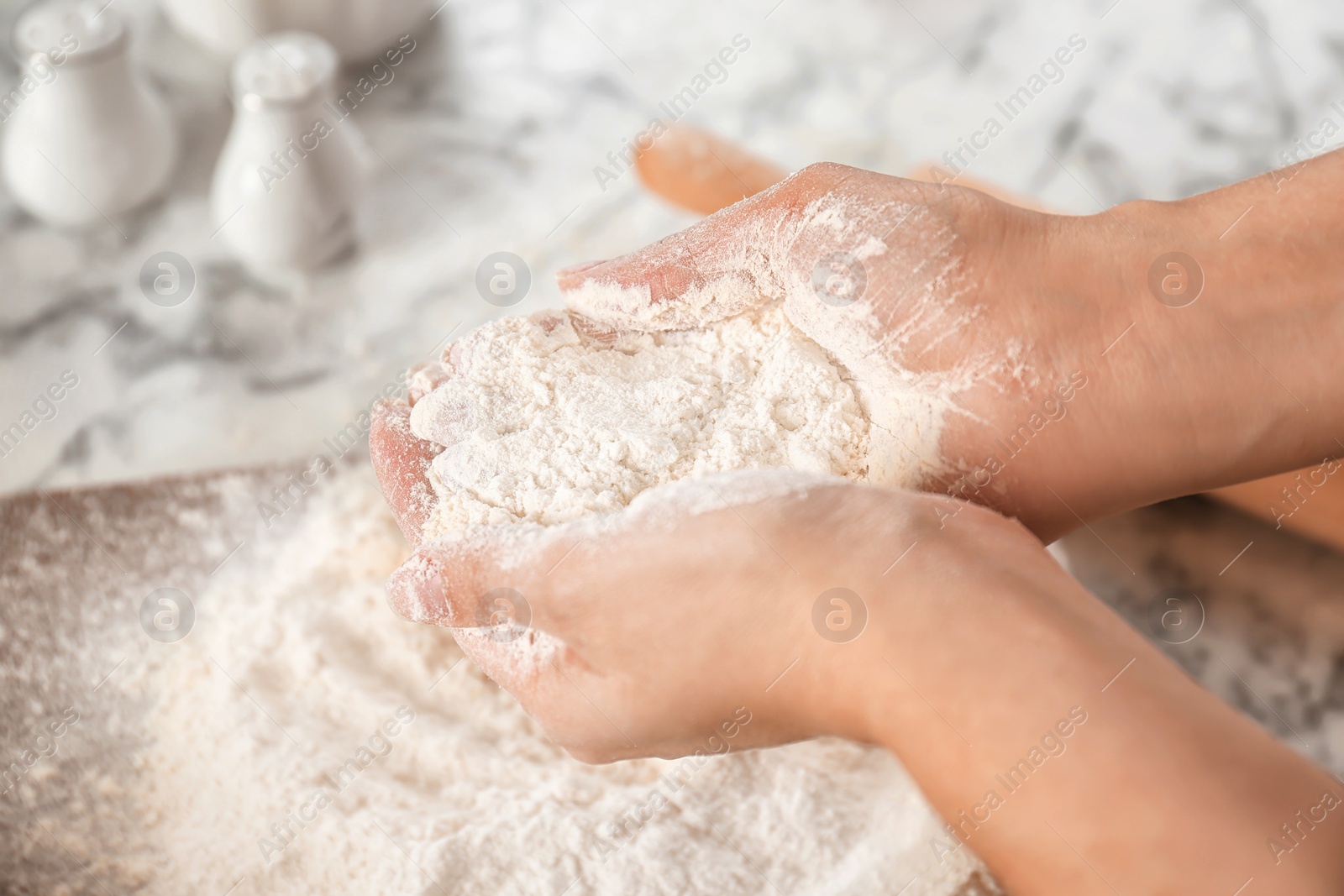 Photo of Woman holding flour over table, closeup