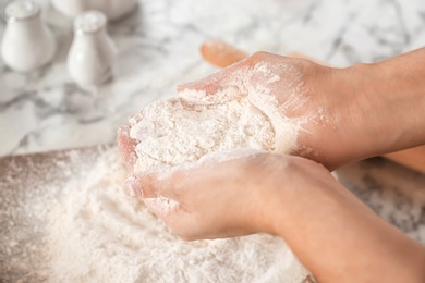 Photo of Woman holding flour over table, closeup