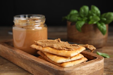 Crispy crackers with delicious meat pate on wooden table, closeup