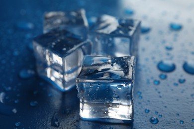 Ice cubes with water drops on blue background, closeup