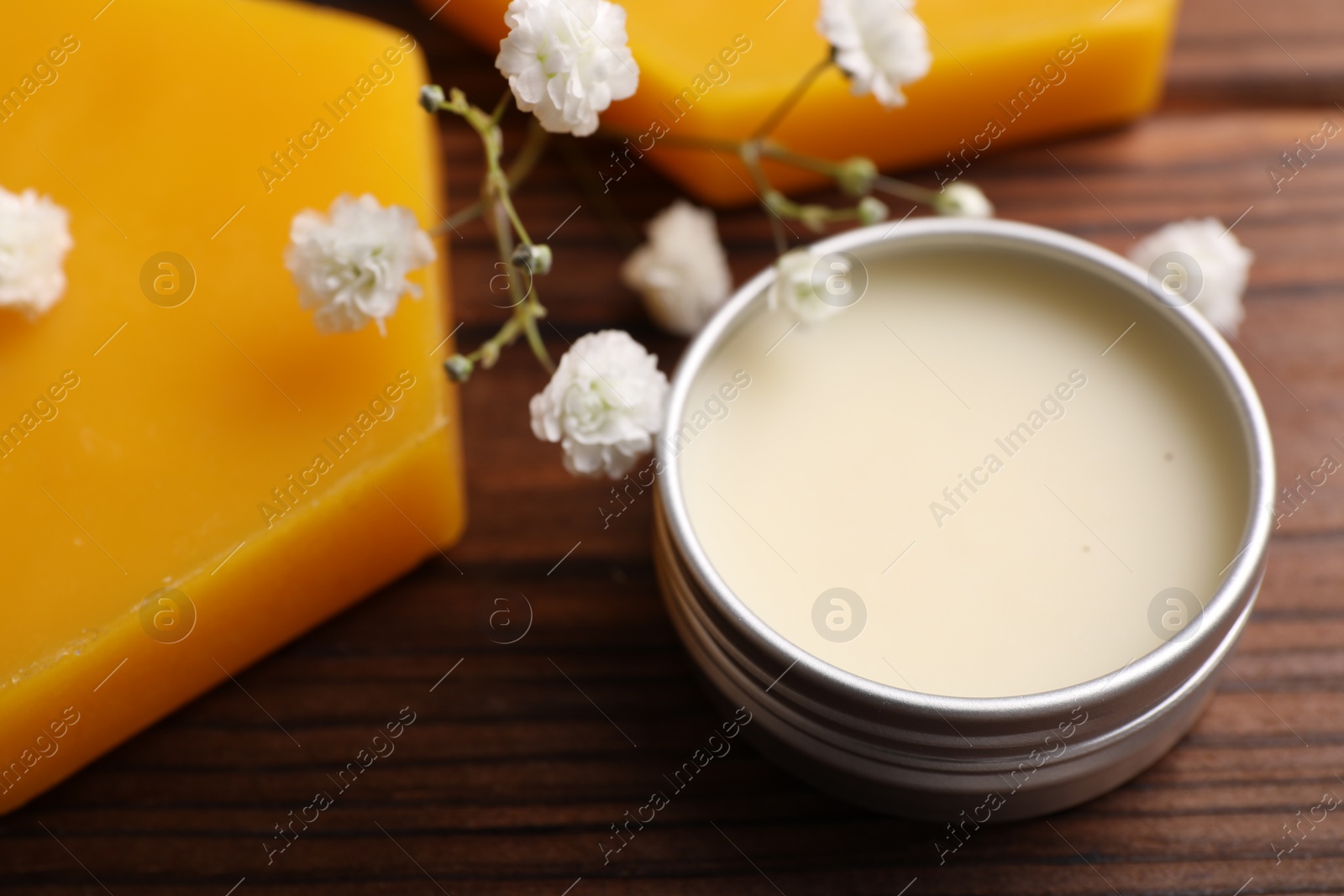 Photo of Lip balm and gypsophila flowers on wooden table, closeup