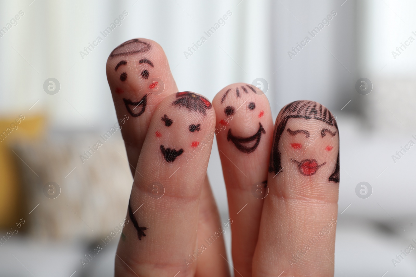 Photo of Four fingers with drawings of happy faces on blurred background