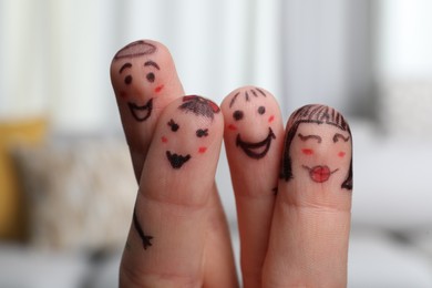 Photo of Four fingers with drawings of happy faces on blurred background