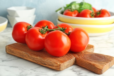 Photo of Wooden board with fresh ripe tomatoes on table