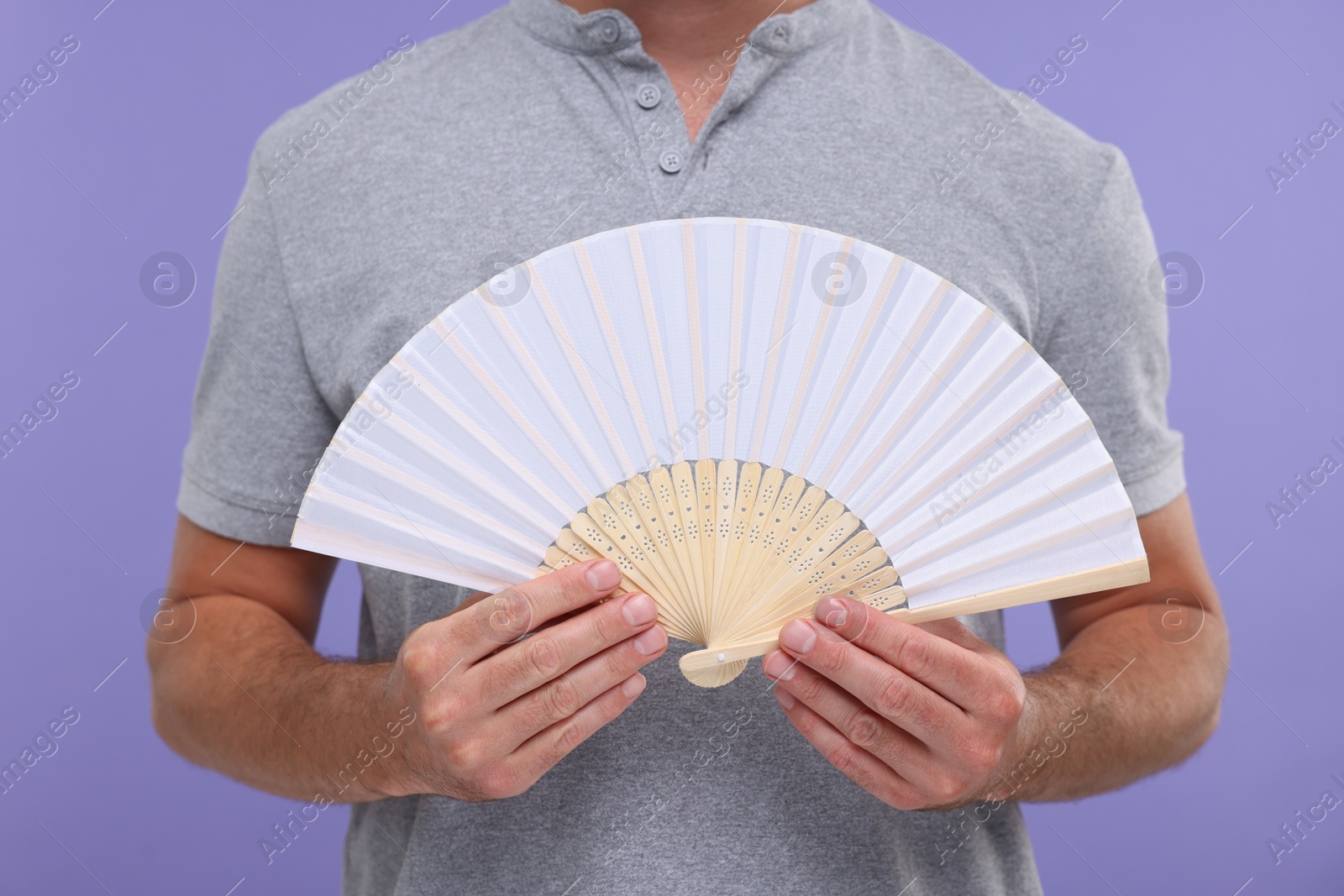 Photo of Man holding hand fan on purple background, closeup