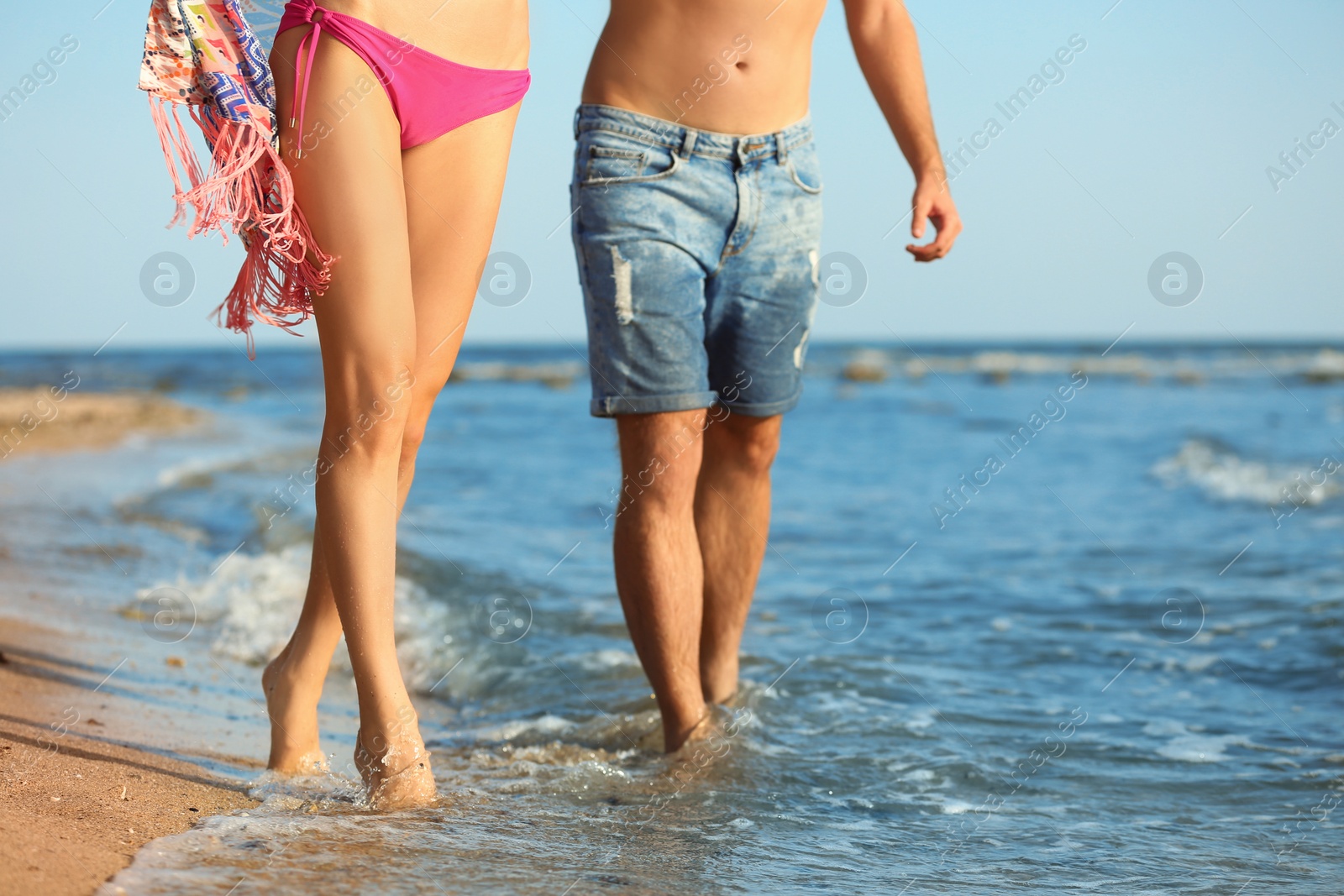Photo of Young couple spending time together on beach, closeup of legs