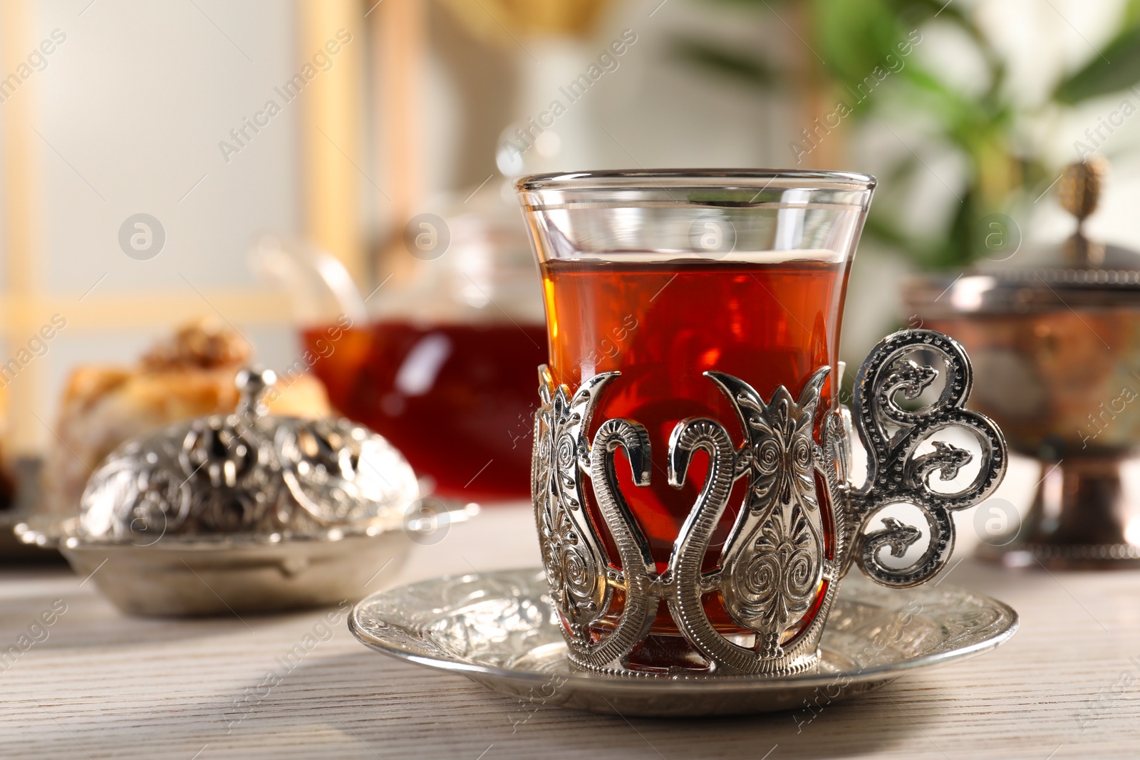 Photo of Glass of traditional Turkish tea in vintage holder on white wooden table, closeup. Space for text