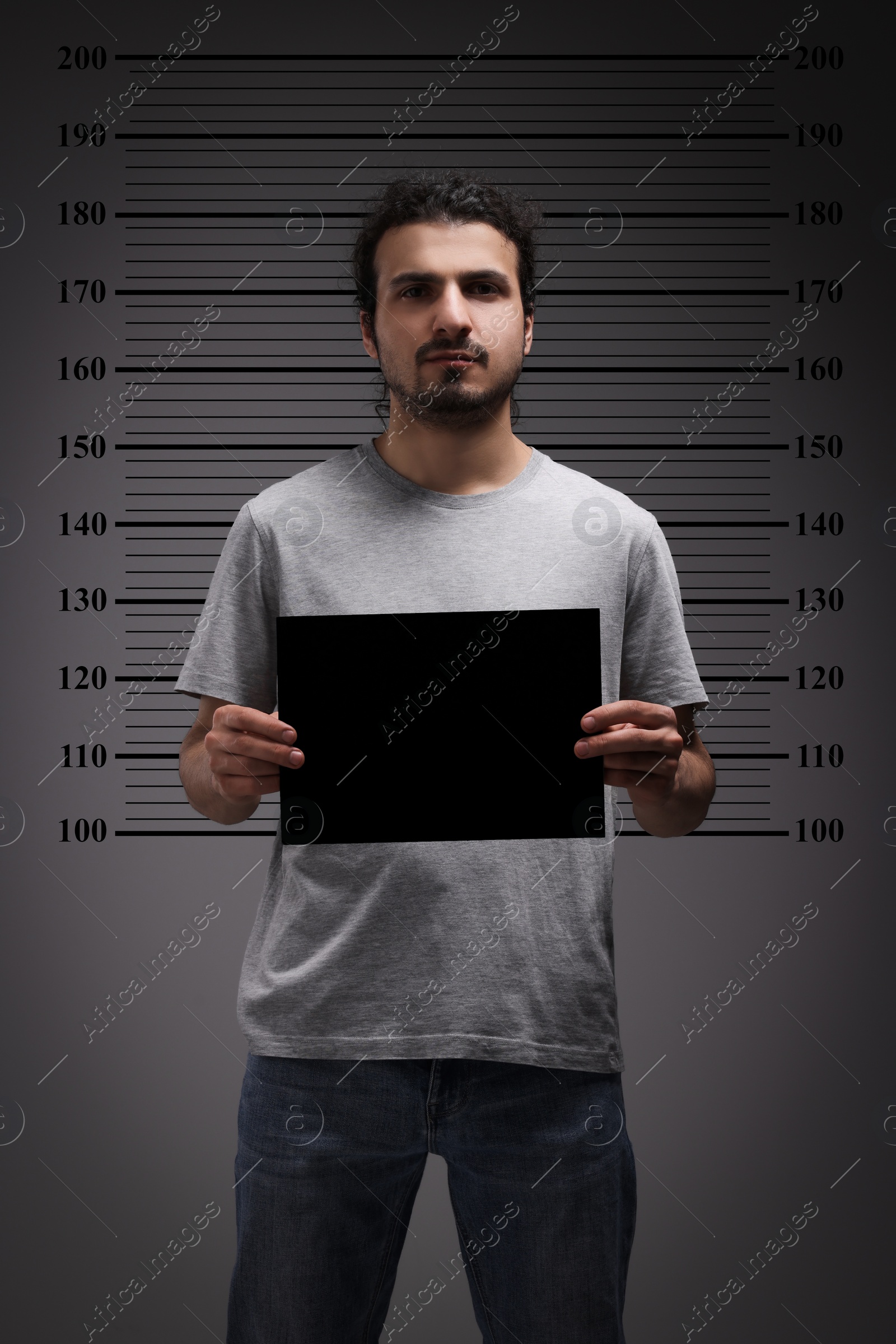 Image of Criminal mugshot. Arrested man with blank card against height chart