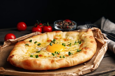 Fresh delicious Adjarian khachapuri with microgreens served on wooden table