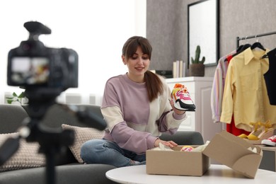 Photo of Smiling fashion blogger showing her shoes while recording video at home