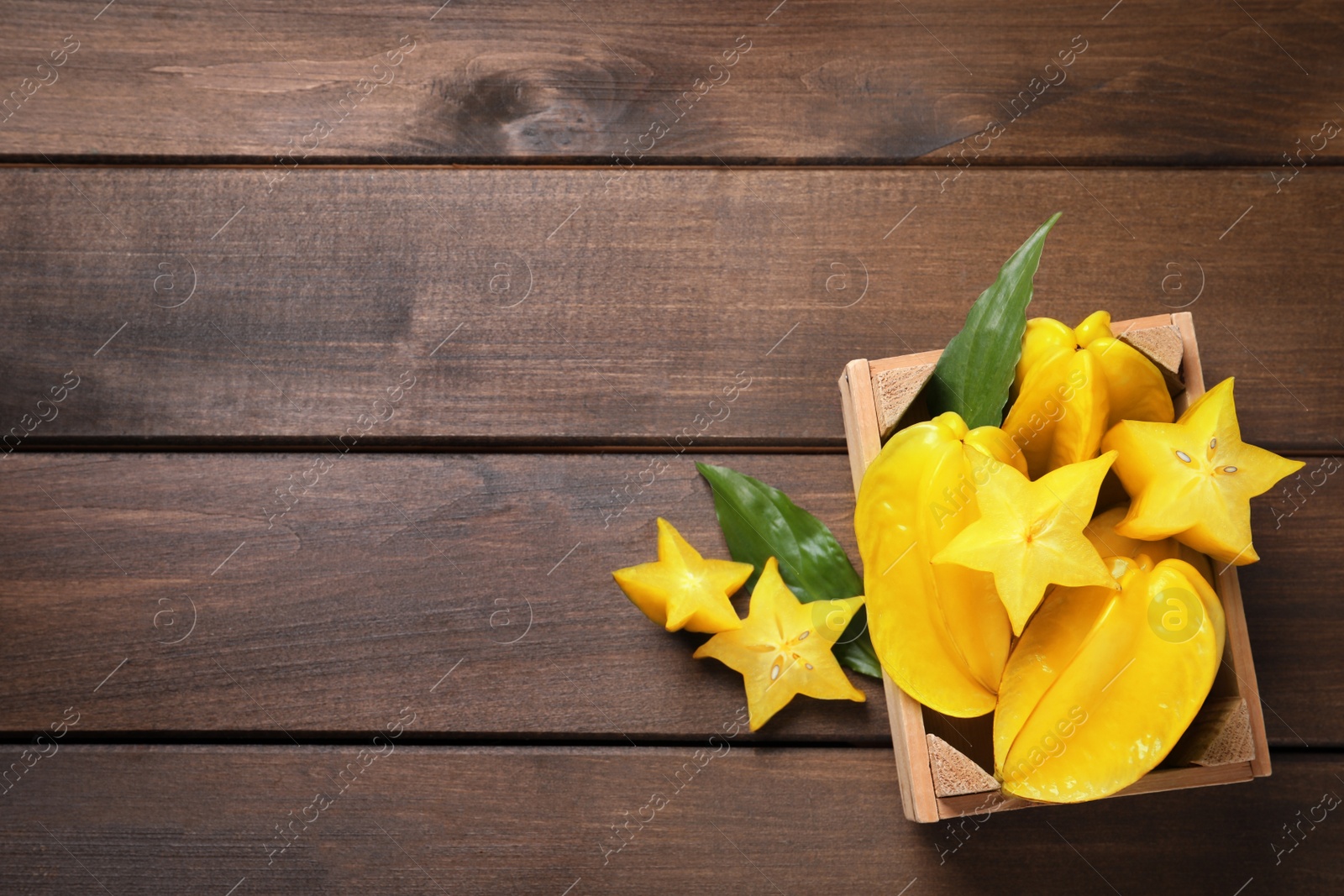 Photo of Delicious carambola fruits on wooden table, flat lay. Space for text