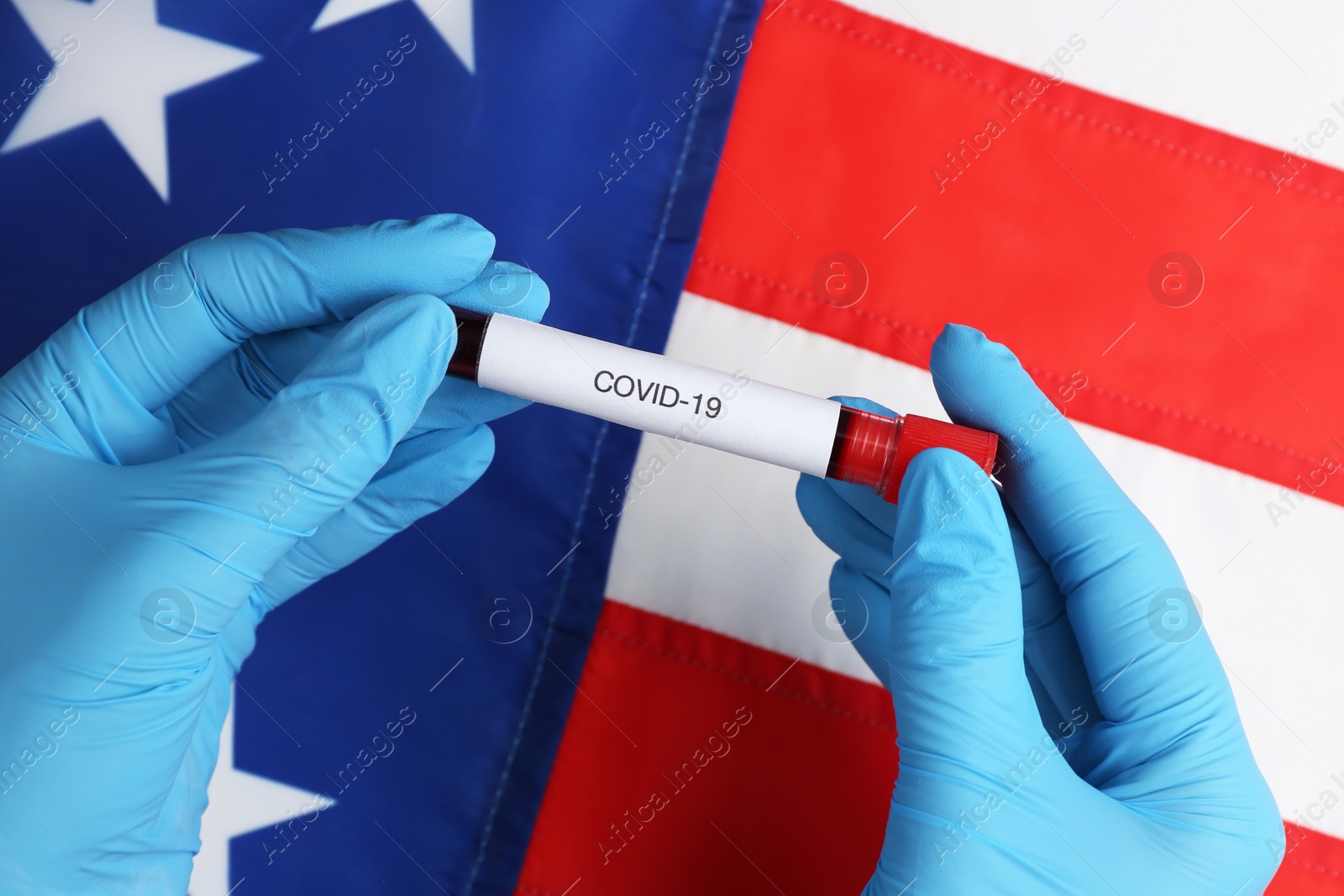 Photo of Scientist holding test tube with blood sample over American flag, closeup. Coronavirus pandemic in USA